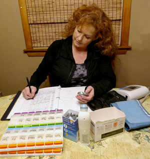 Maria Waters works on filling her parents med planners and tracking their medications.
