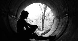 silhouette of a girl sitting in a sewer pipe